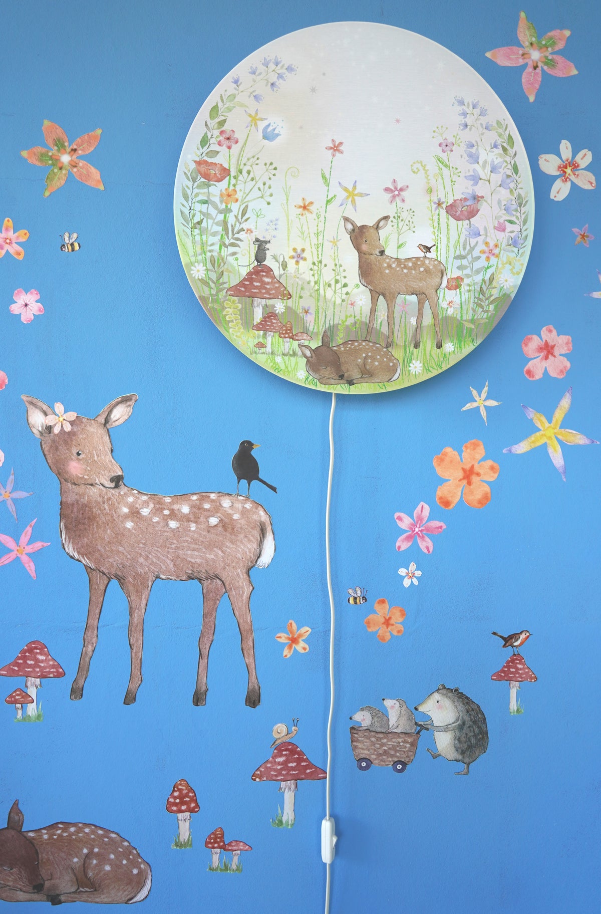 Close-up van Bloemenwei en Hertje & Vrienden muurstickers op blauwe muur met Sprookjestuin wandlamp