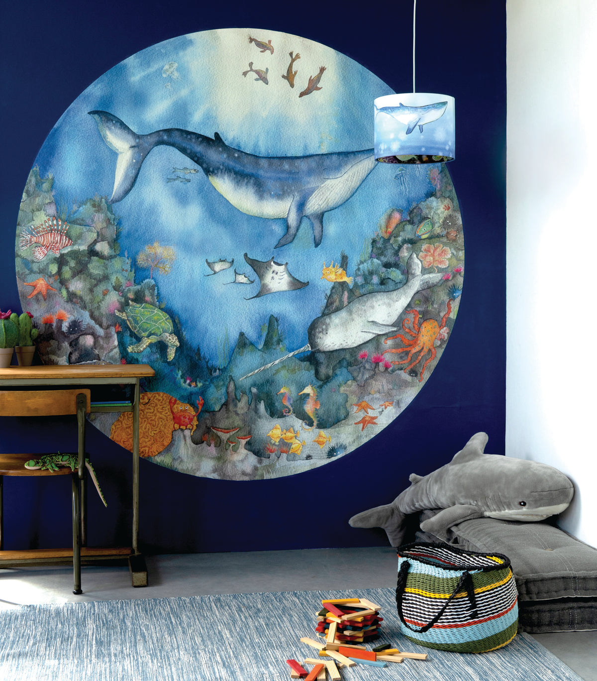 Diepzee Droom behangcirkel van Hartendief op een marineblauwe muur met speelgoedhaai en bureautje in de kinderkamer