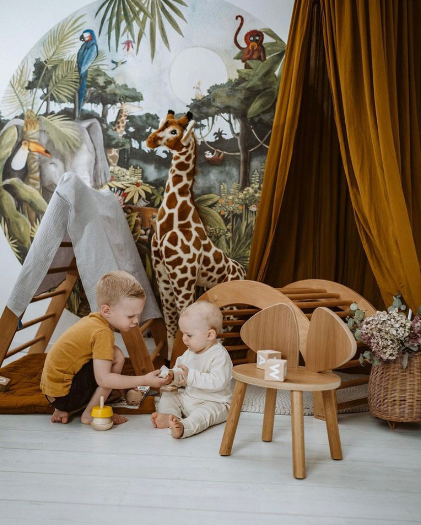 Jungle behangcirkel van Hartendief in een kinderkamer met spelende kinderen en een knuffelgiraffe