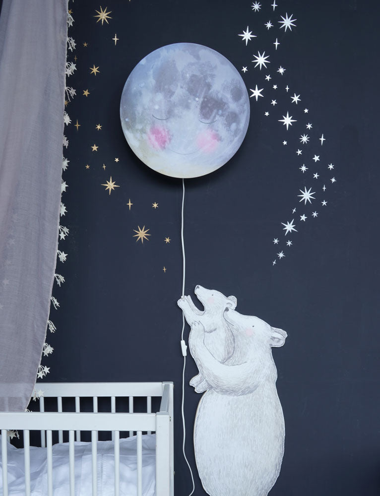 Nahaufnahme des Eisbären-Wandtattoos an dunkler Wand mit silbernen und goldenen Sternen und der Schlafender Mond Wandlampe