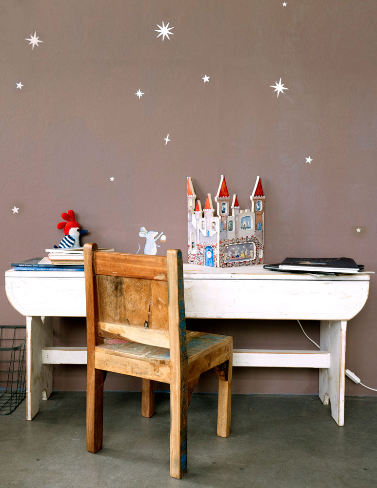 Zilveren sterren en maan muurstickers van Hartendief op een bruine muur naast een bureau en de Muizenkasteel lamp