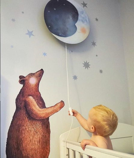 Bär Wandtattoo neben einem Kind, das die Äuglein-zu Wandlampe im Kinderzimmer einschaltet