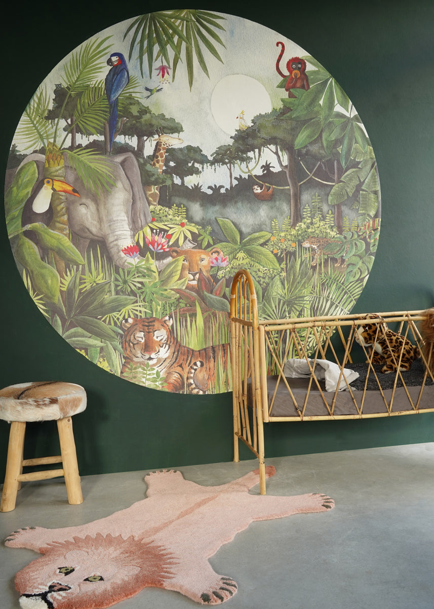 Jungle behangcirkel van Hartendief op een donkergroene muur met rotan bedje en een leeuwenvel kleed